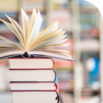 A stack of 4 books with another book that is open on top