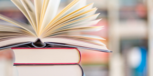 A stack of 4 books with another book that is open on top