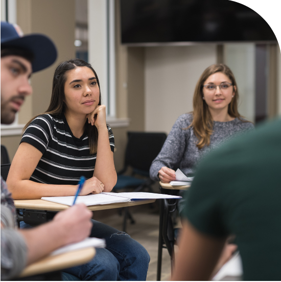 Four people sitting at desks in what looks like a classroom. They seem to be having a discussion