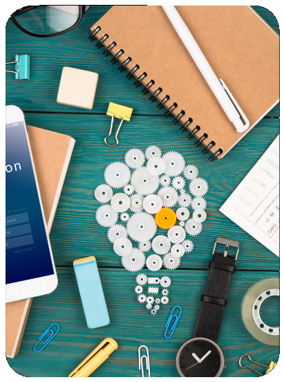 A picture of random items on a table. The items include a notebook, some plastic gears, paper clips, a watch, a pencil, a phone, and some glasses
