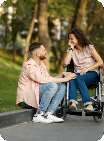 A picture of a person sitting on a curb talking to another person in a wheelchair