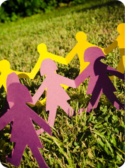 A picture of paper people in various colours holding hands in the grass