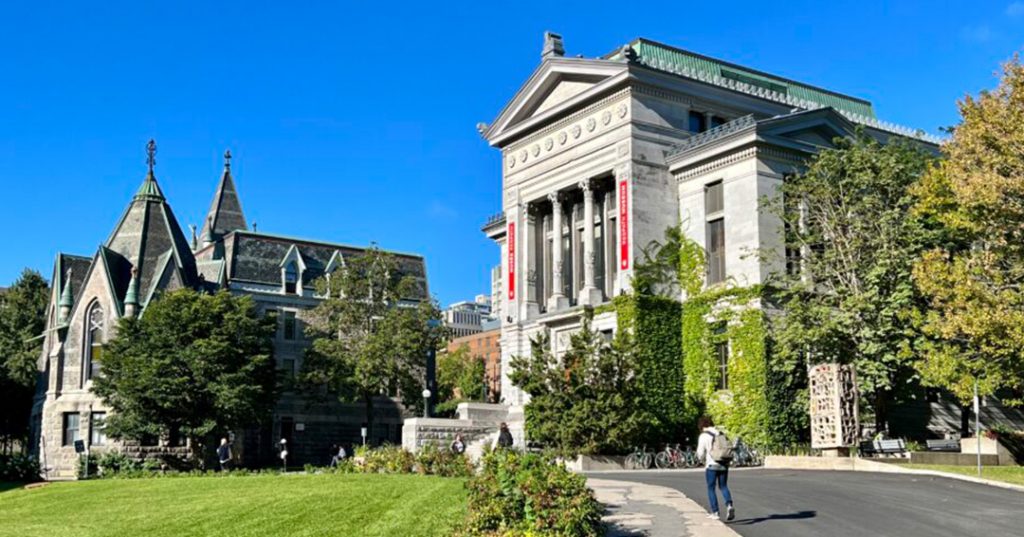 mcgill university arts building on a sunny day. There is a lot of greenery and a piercing blue sky.