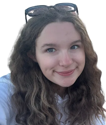 Jasmine has long, curly brown hair and glasses on top of her head. She's smiling directly at the camera.
